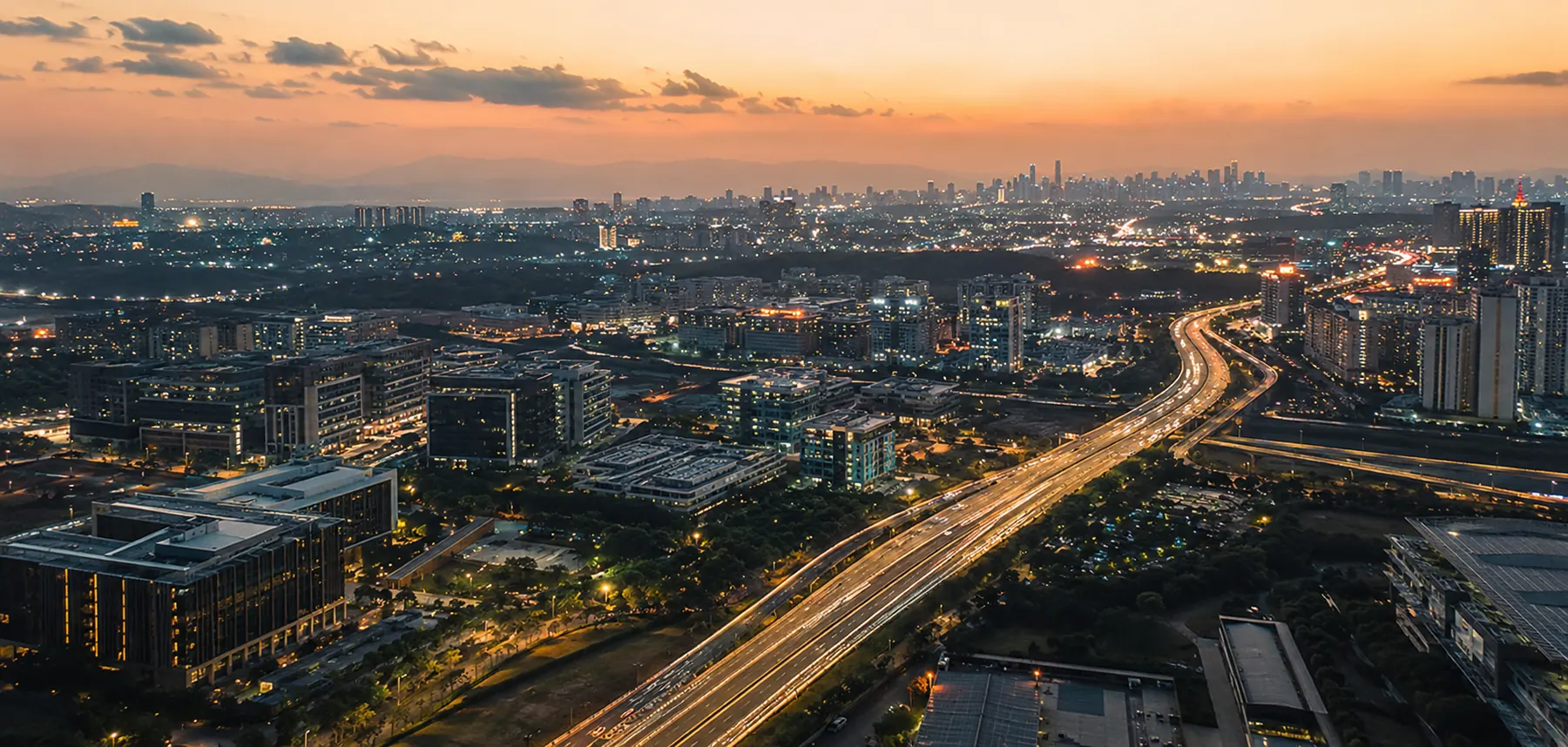 An aerial view of an Indian city at dusk, arterial roads lit across the network